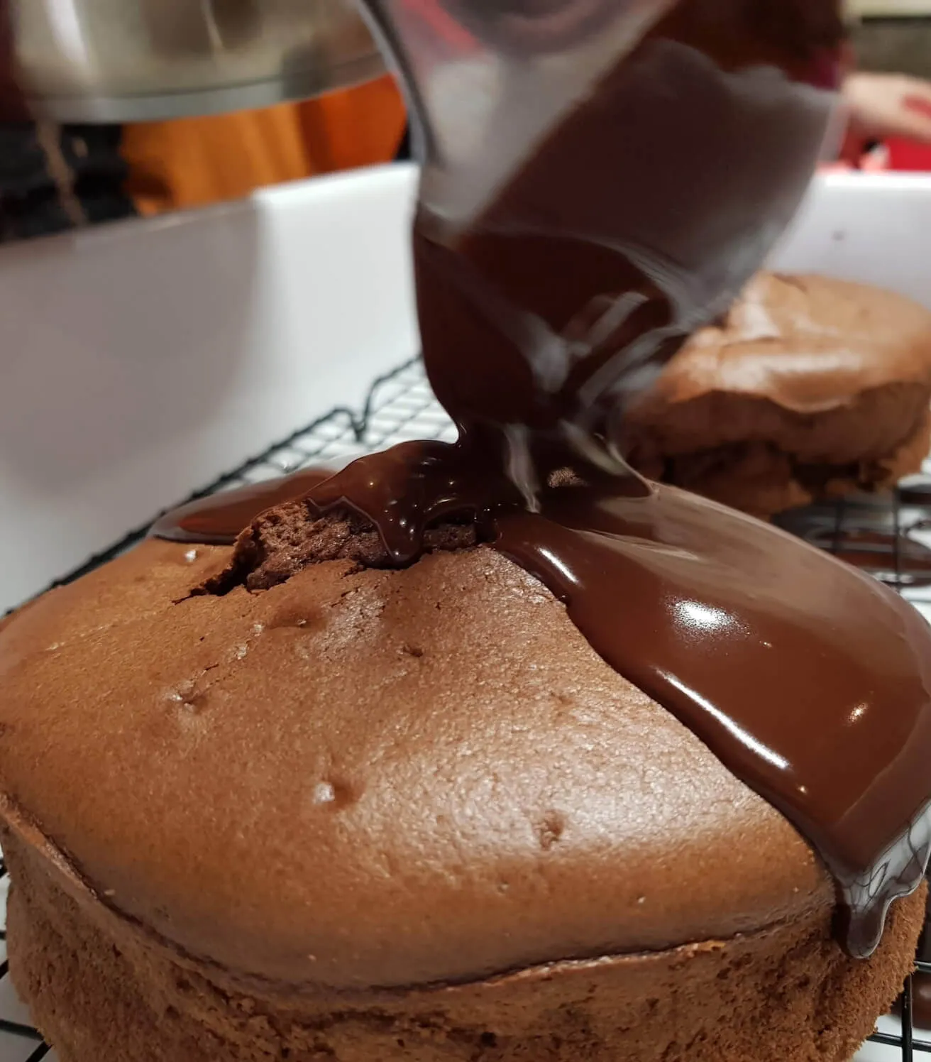 Una persona vierte chocolate encima de un pastel.